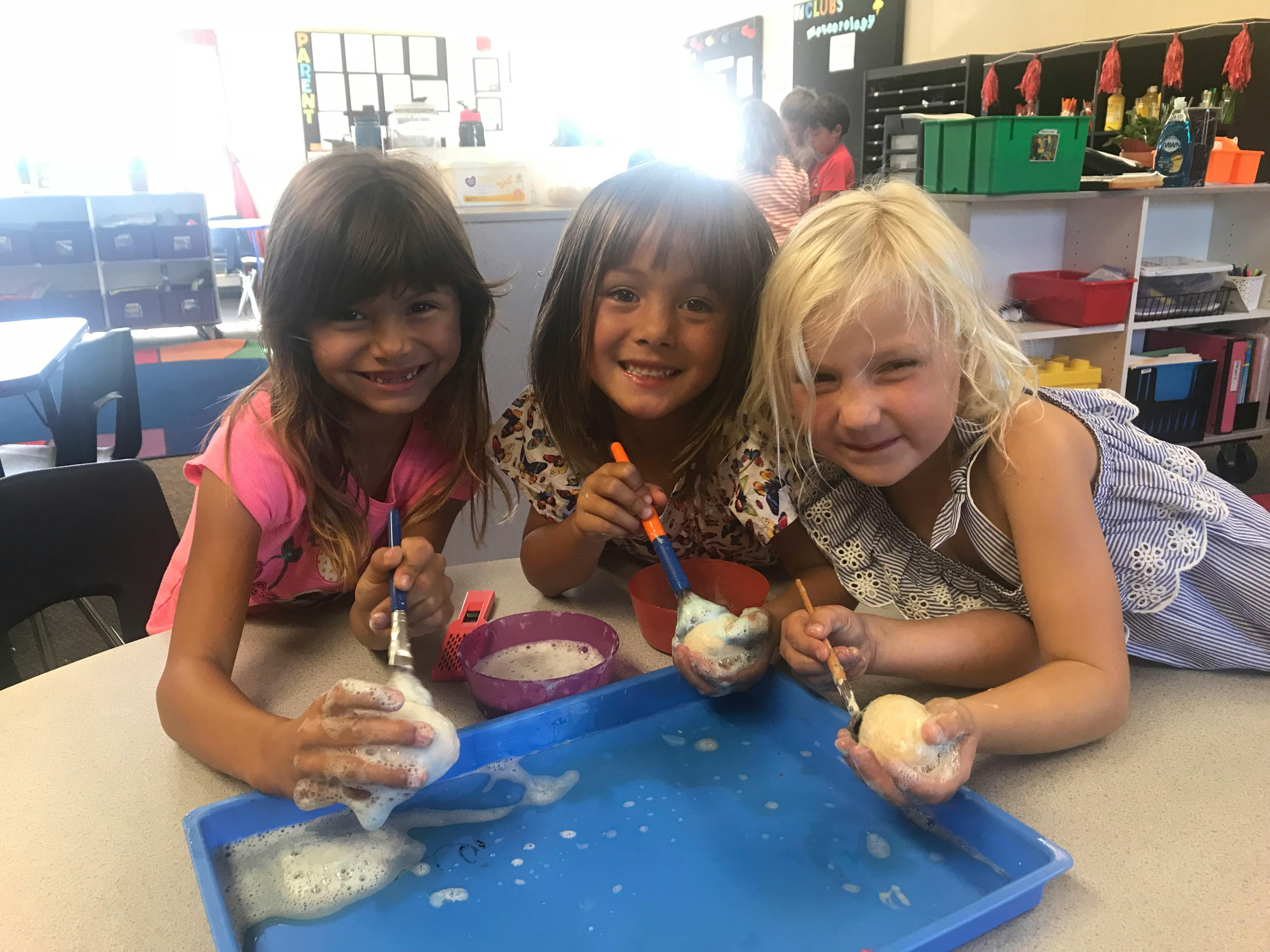 Three children painting objects at a table