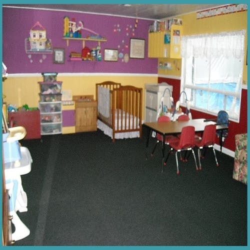 Childcare room with a crib, small chairs, and table