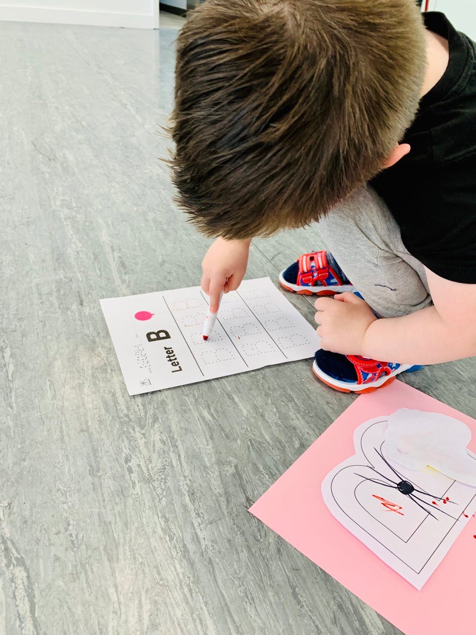 Child writing on a paper with "Letter B" printed on it