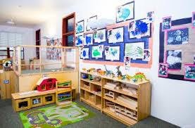 Classroom with children's artwork on walls and wooden shelves with toys