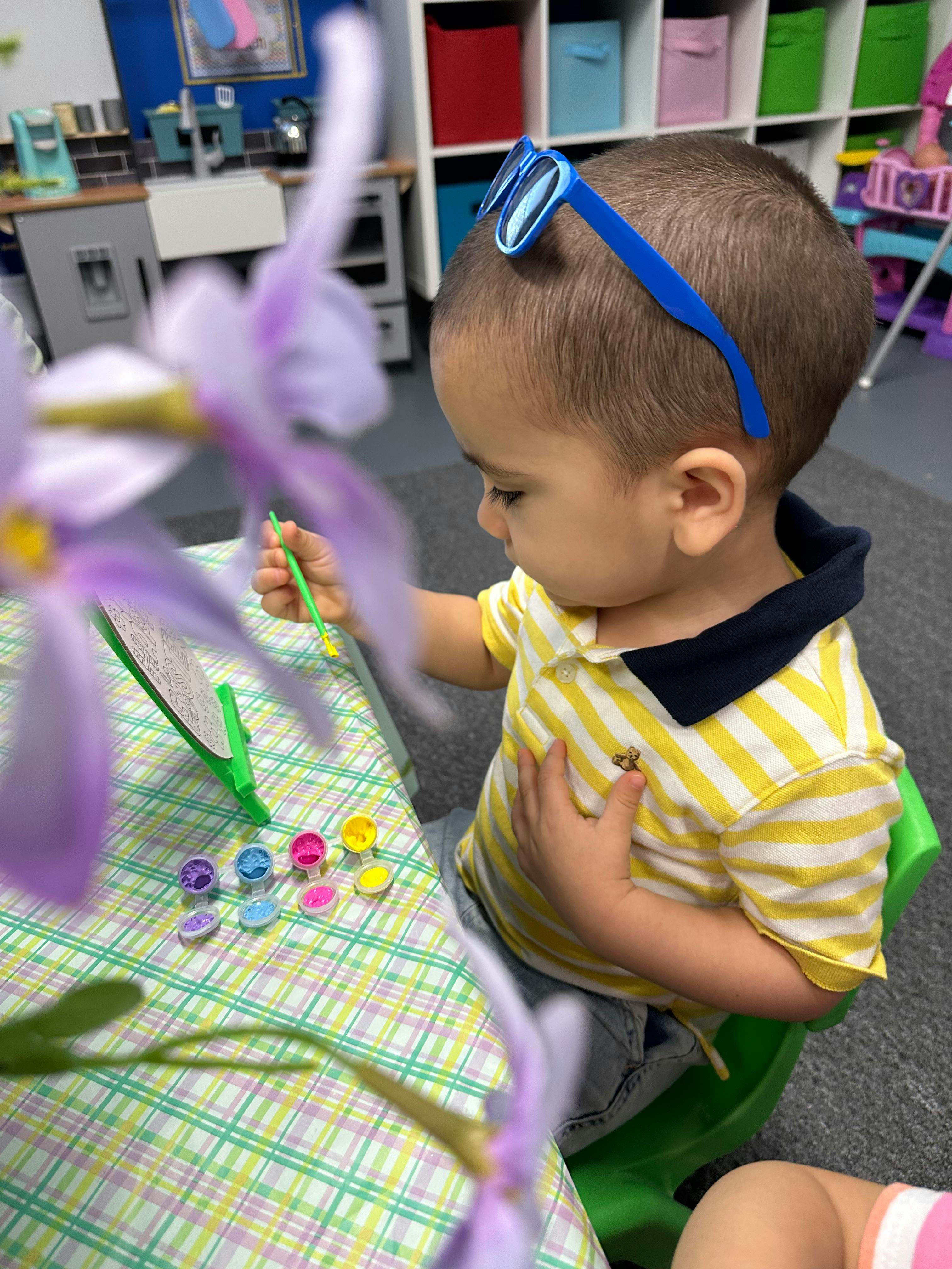 Child painting at a table in a classroom