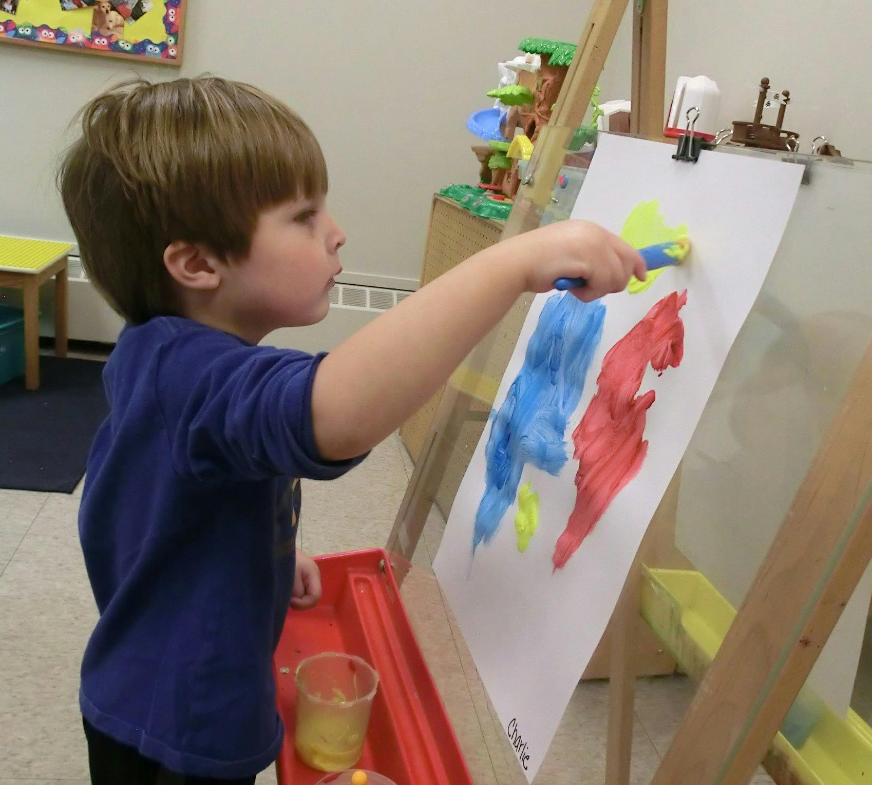 Child painting on an easel in a classroom