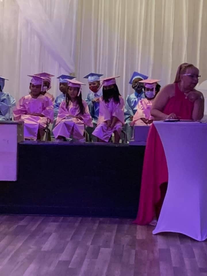 Children in graduation caps and gowns sitting on a stage