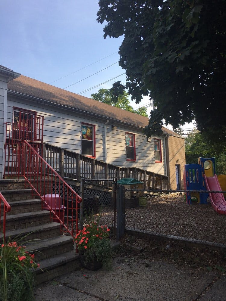 Building exterior with red railings, stairs, and a ramp leading to a playground