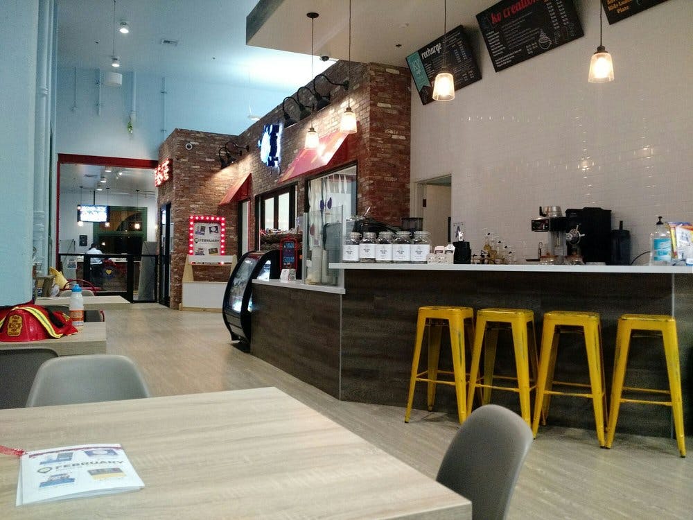Interior of a cafe with a counter, yellow bar stools, and tables