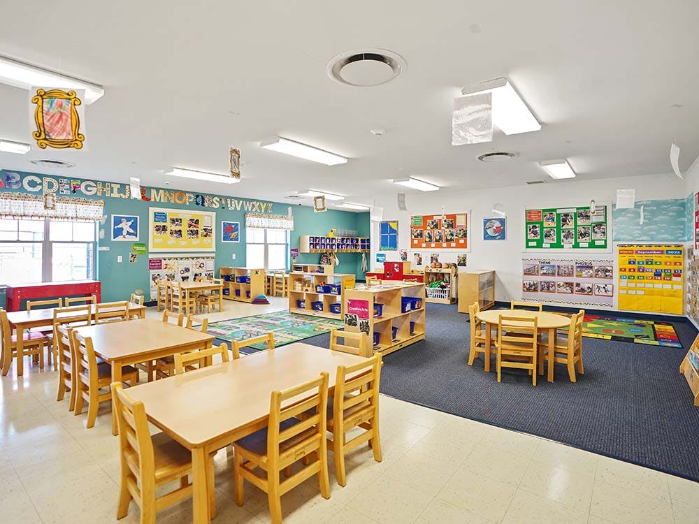empty preschool classroom with small tables and chairs