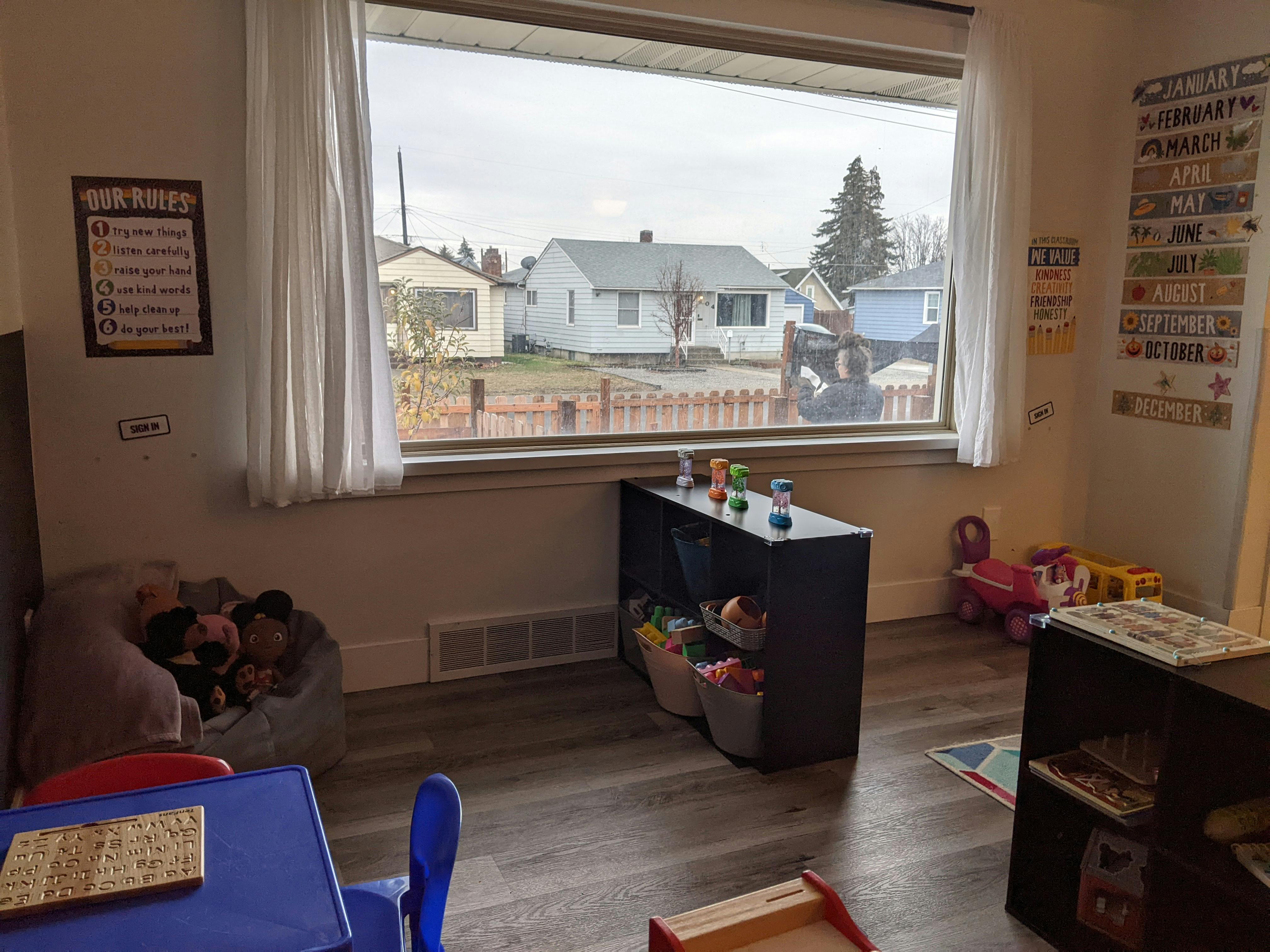 Playroom with toys, small table and chairs, and a large window