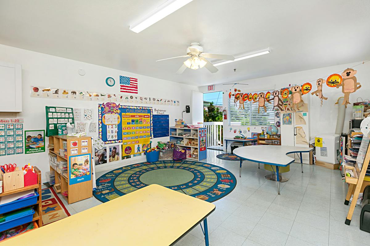 A classroom with a circular rug, tables, and decorations