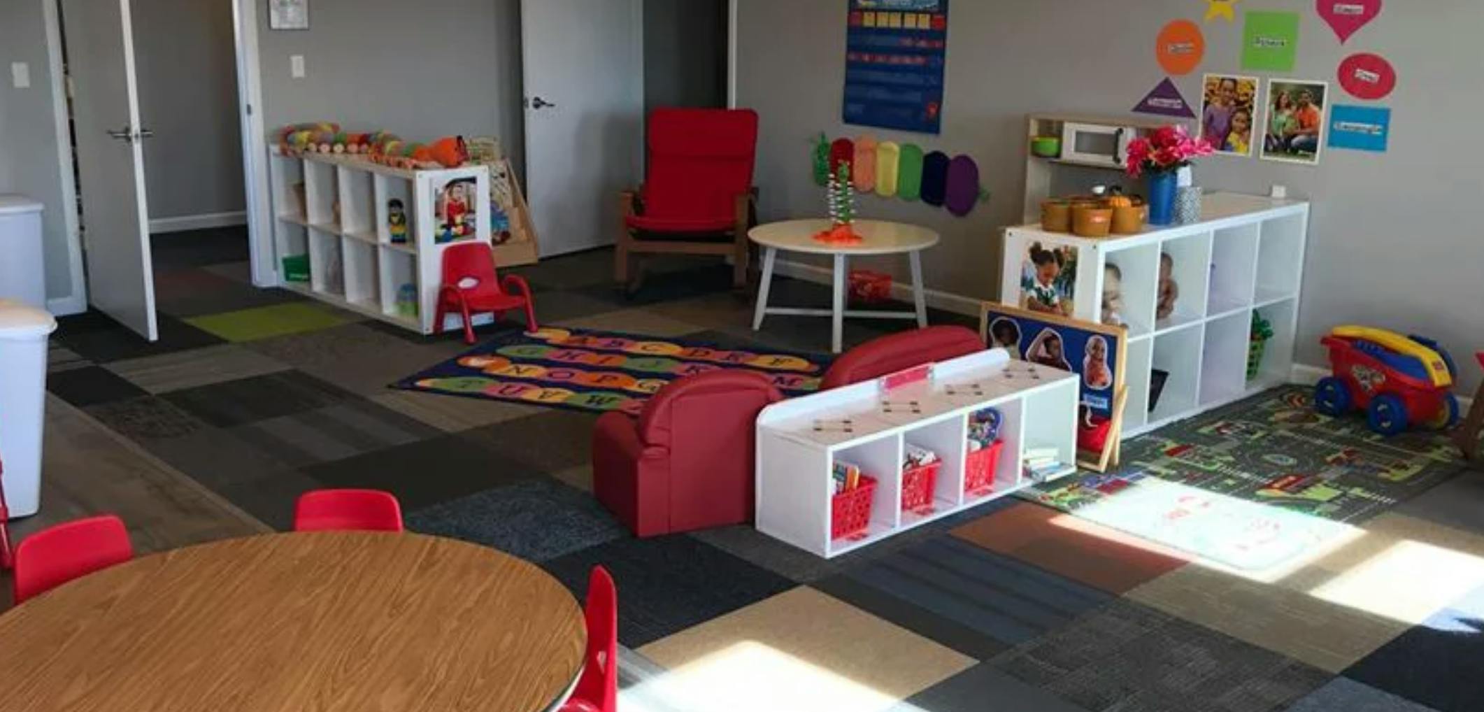 Playroom with small tables, chairs, and storage shelves with toys
