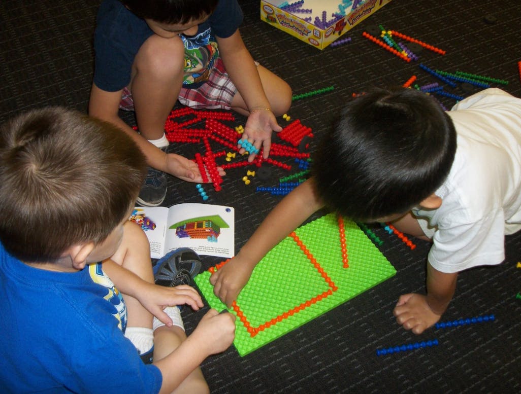 Three children playing with building blocks on the floor