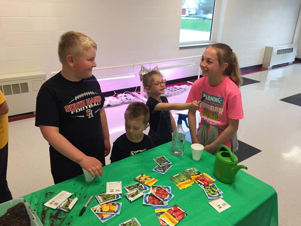 Four children around a table with seed packets and gardening supplies