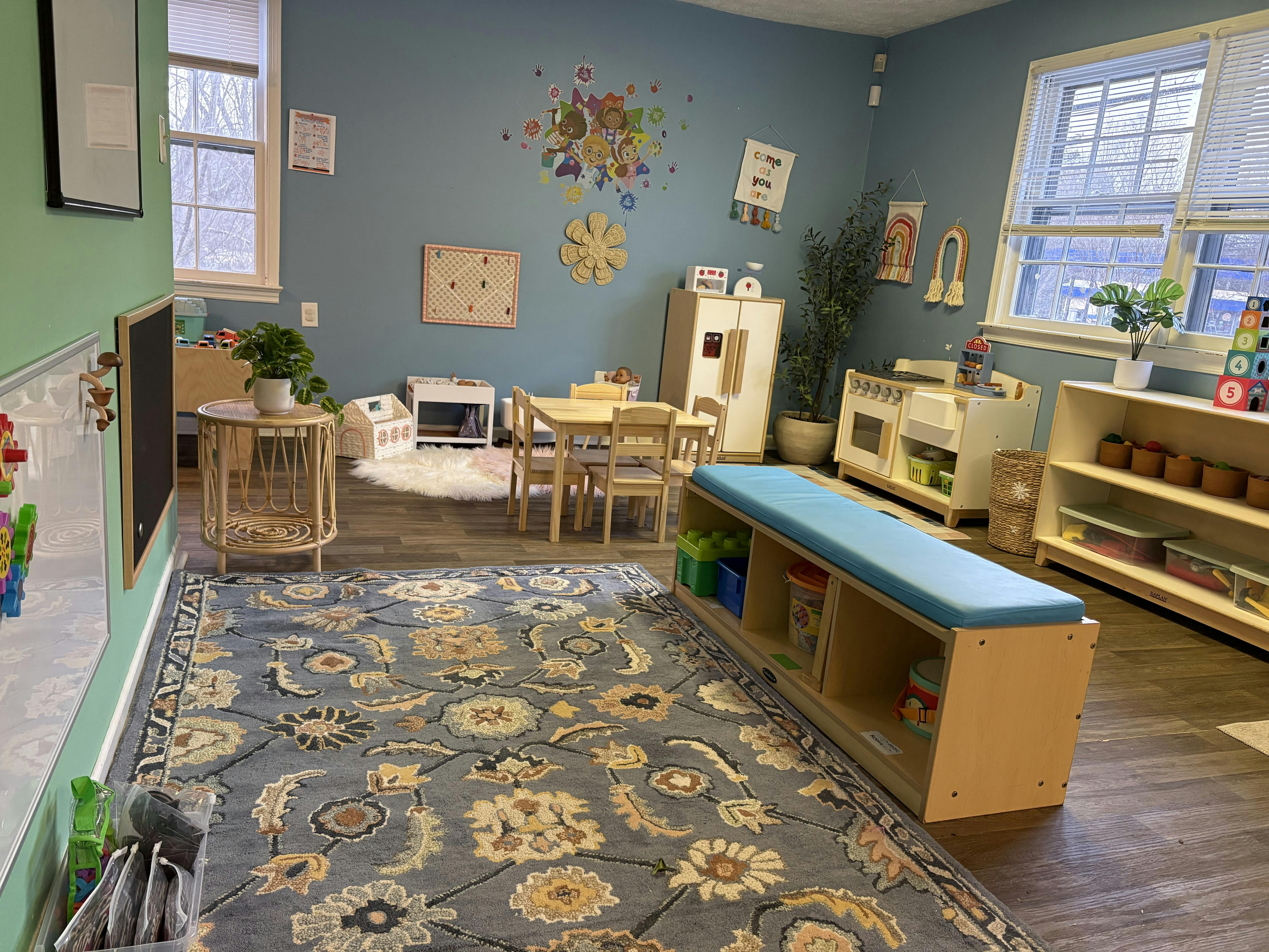 A playroom with child-sized furniture and toys, including a rug with rug on the floor