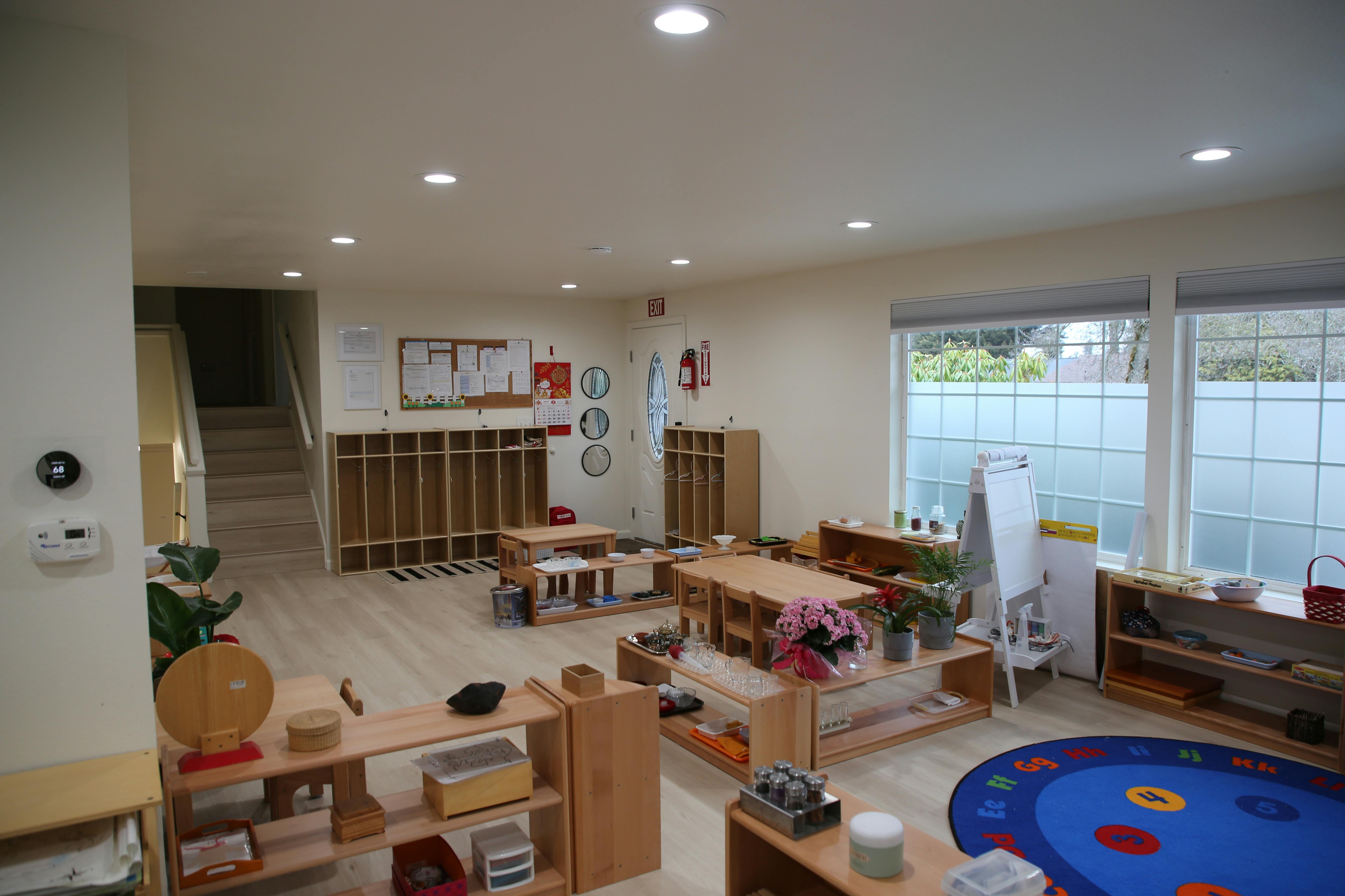 Empty classroom with small tables, chairs, and shelves with learning materials