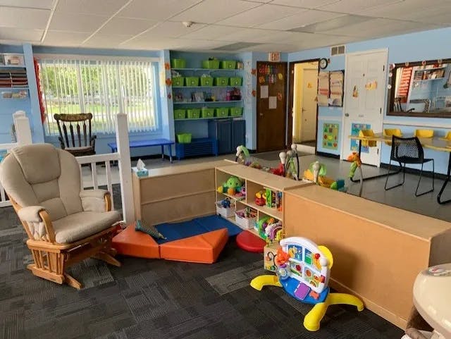 Childcare room with a rocking chair, play mats, and toy shelves