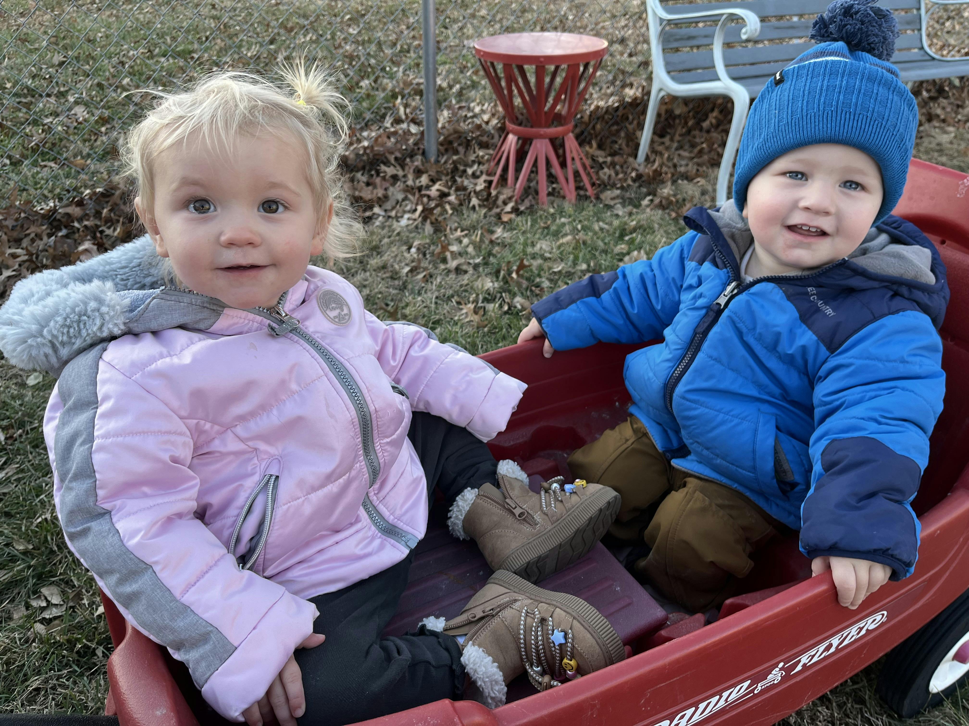Two children sitting in a red wagon