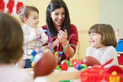 Person clapping with two children playing with toys