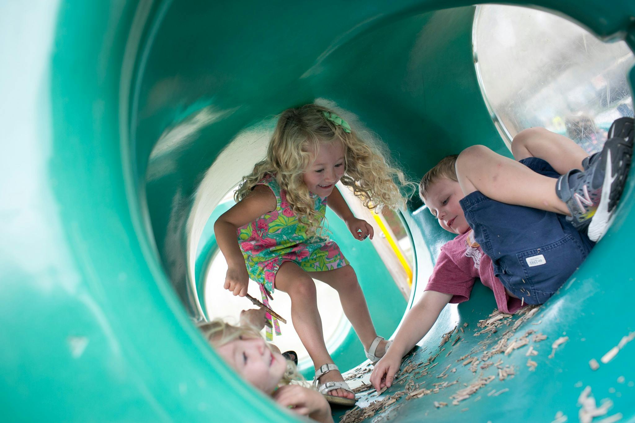 Children playing inside a green tunnel slide