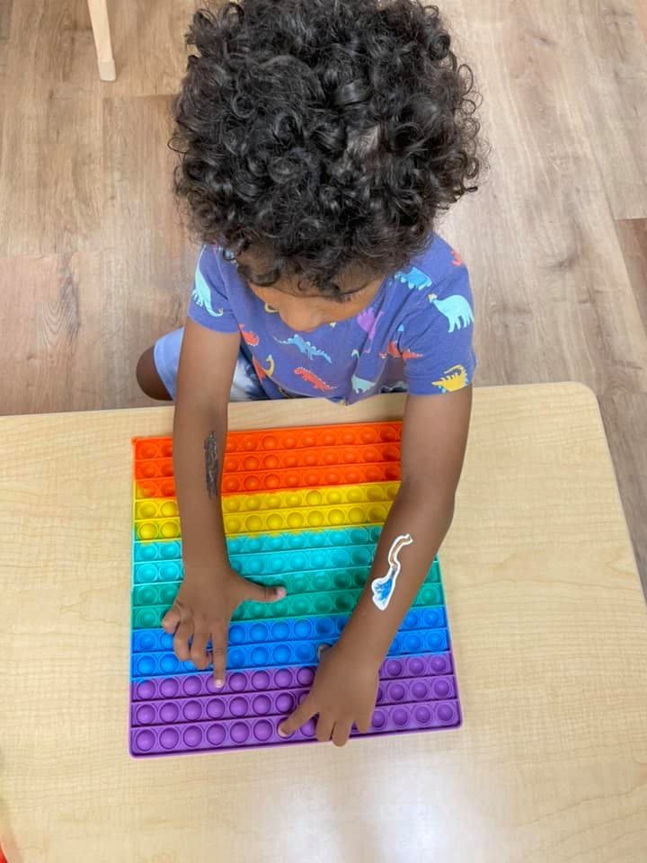 Child playing with a colorful pop-it toy on a table