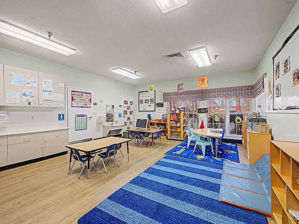 Classroom with tables, chairs, a blue striped rug, and wall decorations