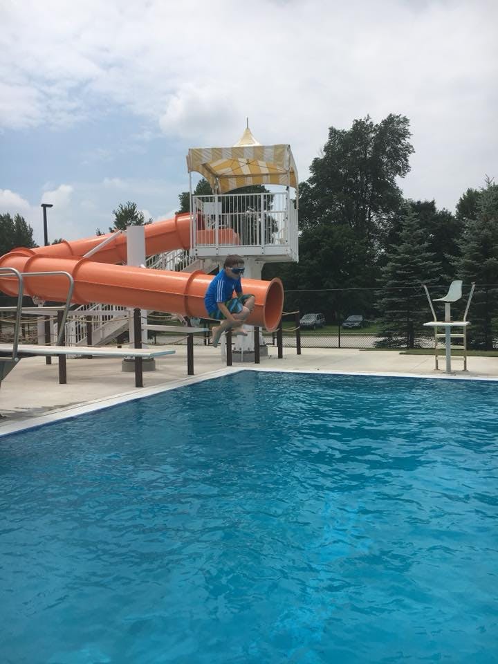 Child on a water slide about to enter a swimming pool