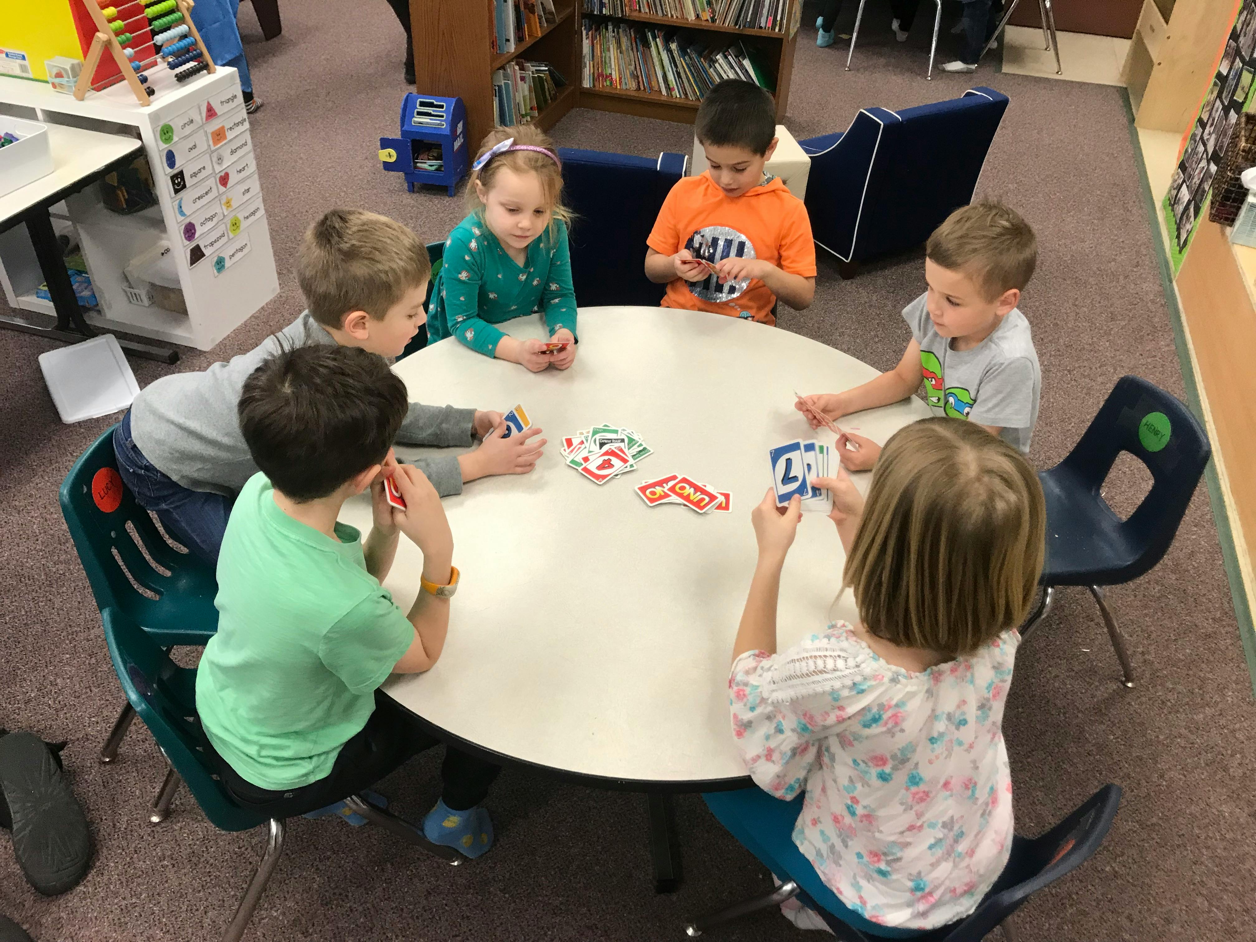 Children playing cards at a round table in a classroom