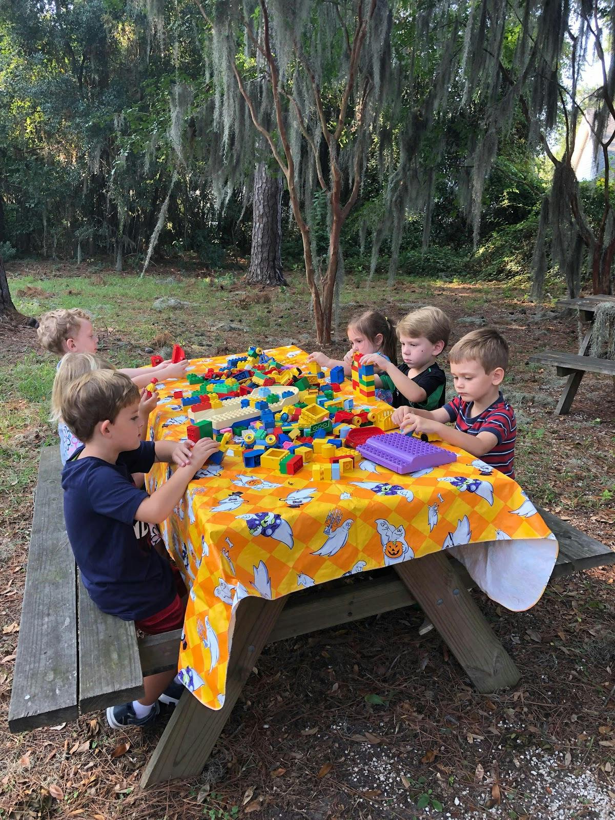 Children playing with colorful building blocks at a picnic table outdoors