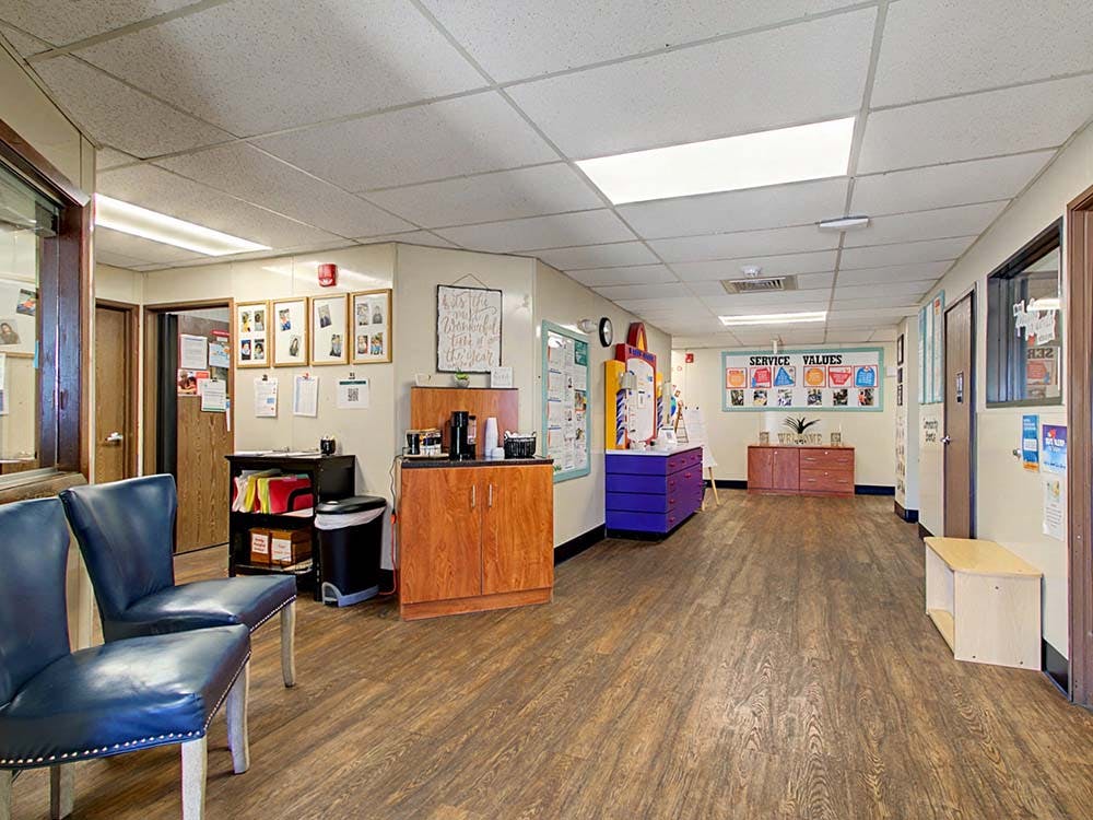 Hallway with chairs, coffee station, and bulletin boards