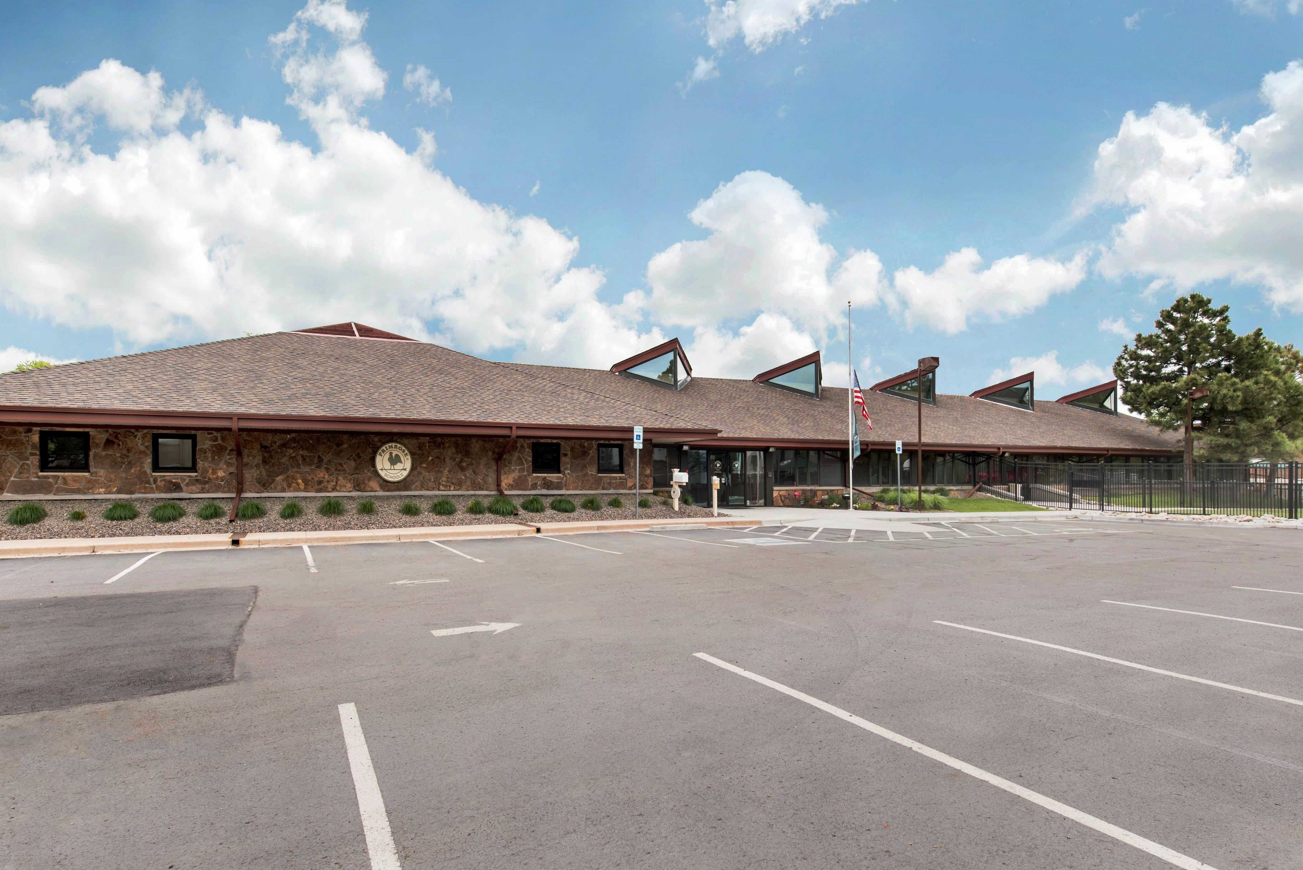 Single-story building with a brown roof and stone facade, large parking lot