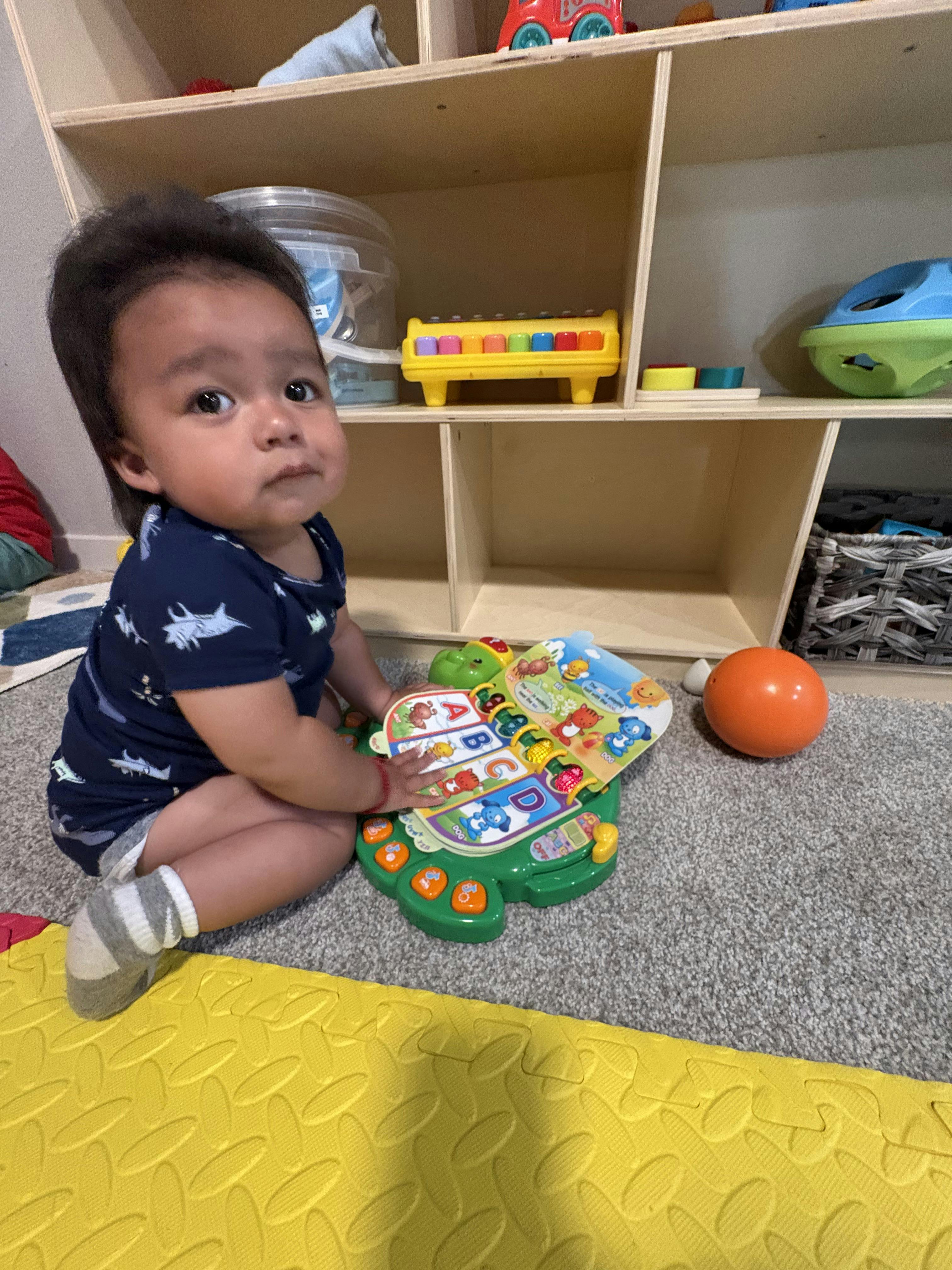 Child sitting on a carpet playing with an interactive alphabet toy