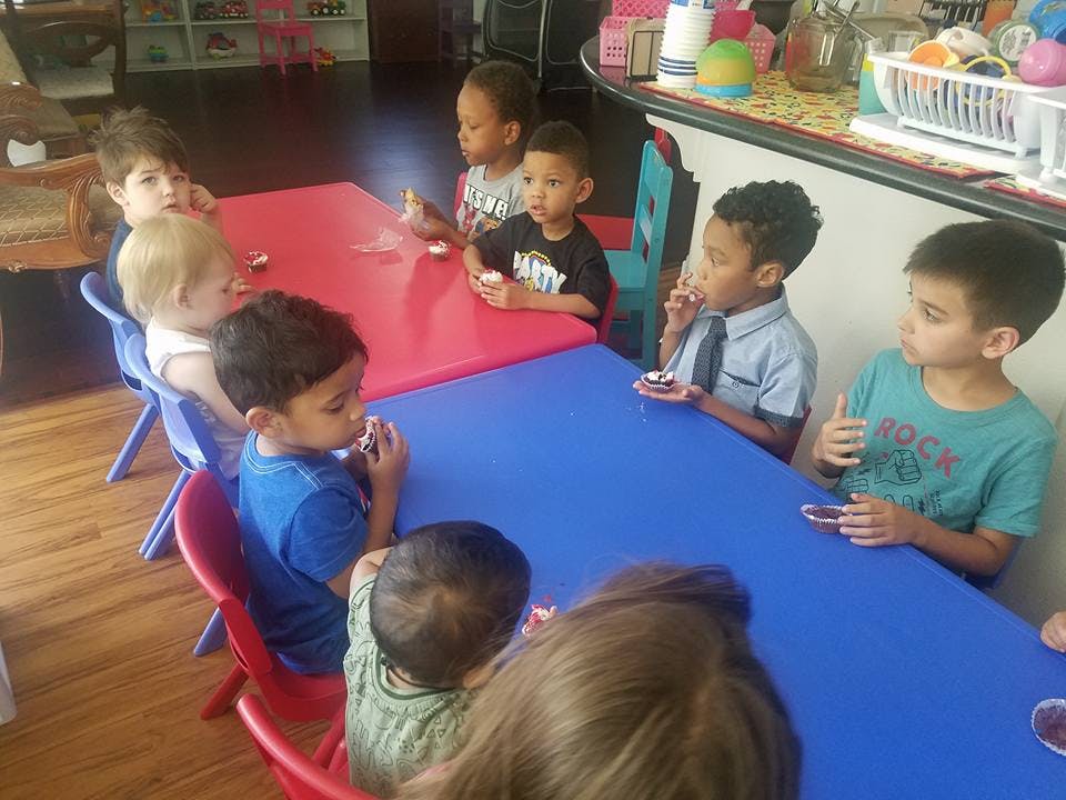 Children sitting at red and blue tables