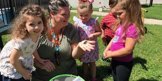 Adult and children gathered around an object outdoors