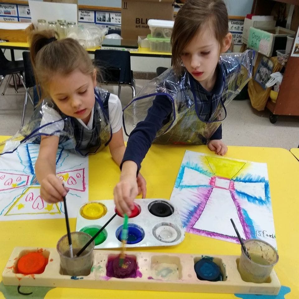 Two children painting with watercolors at a table