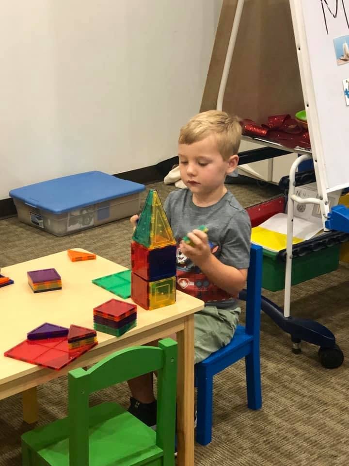 Child playing with colorful magnetic blocks at a table