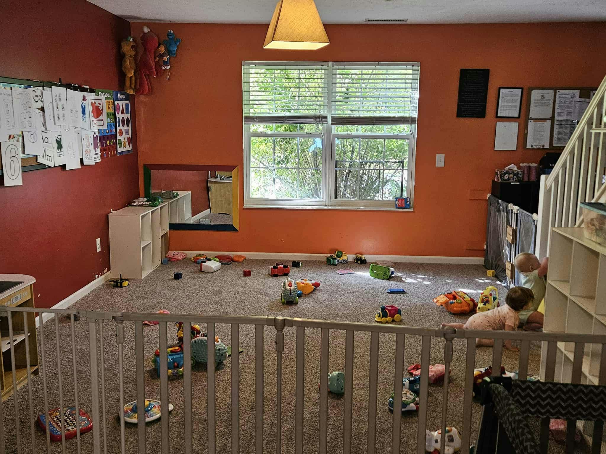 Child playing on a carpeted floor with toys in a room with orange walls
