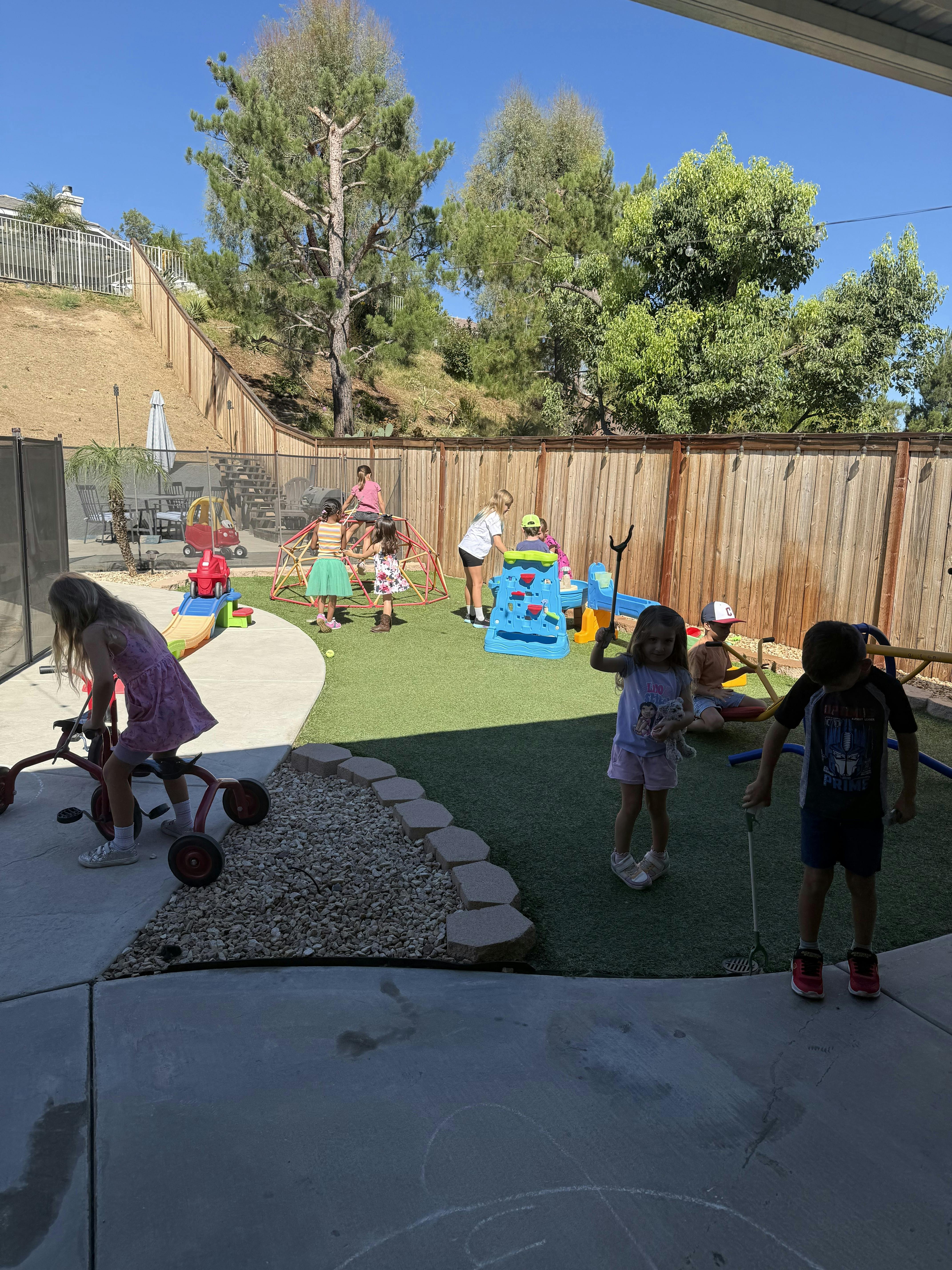 Group of children playing in a backyard with toys and playground equipment