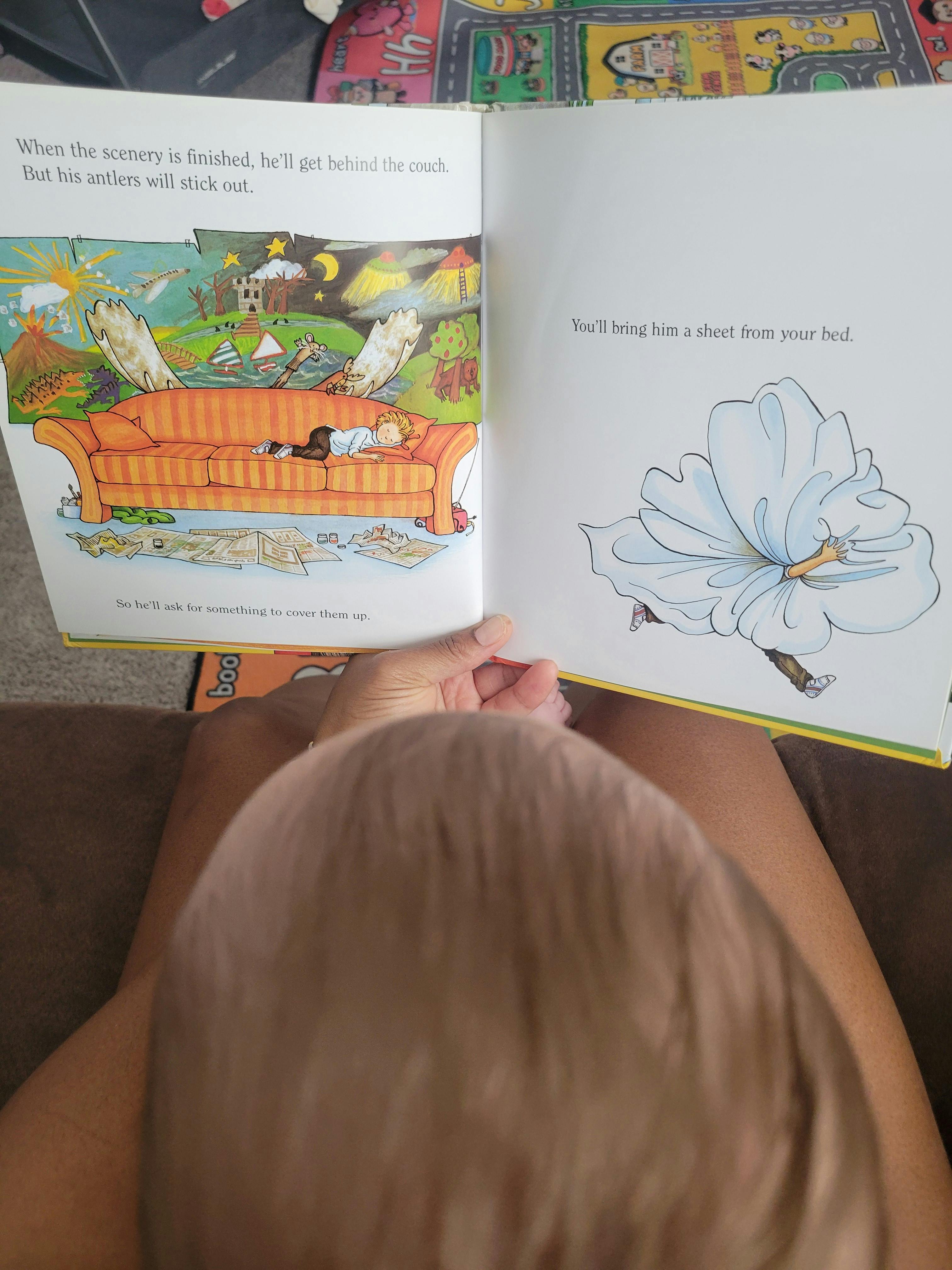 Person holding an open children's book featuring illustrations and text
