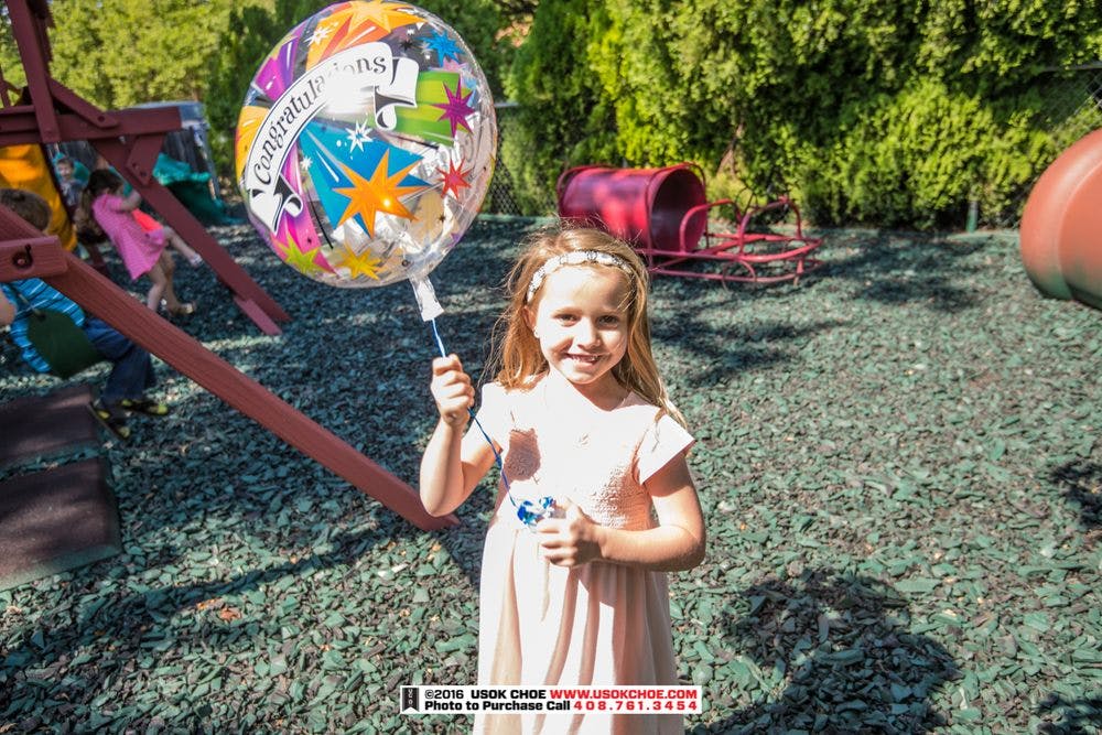 Child holding a clear balloon with "Congratulations" text