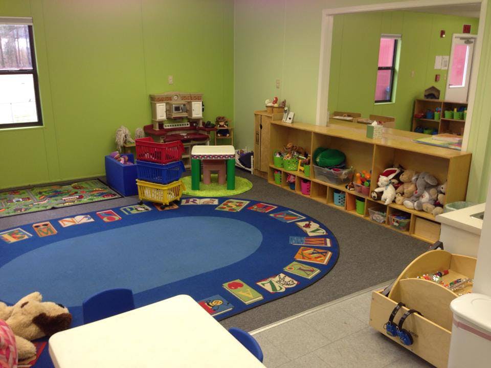 Playroom with a blue oval rug, toys, and shelves