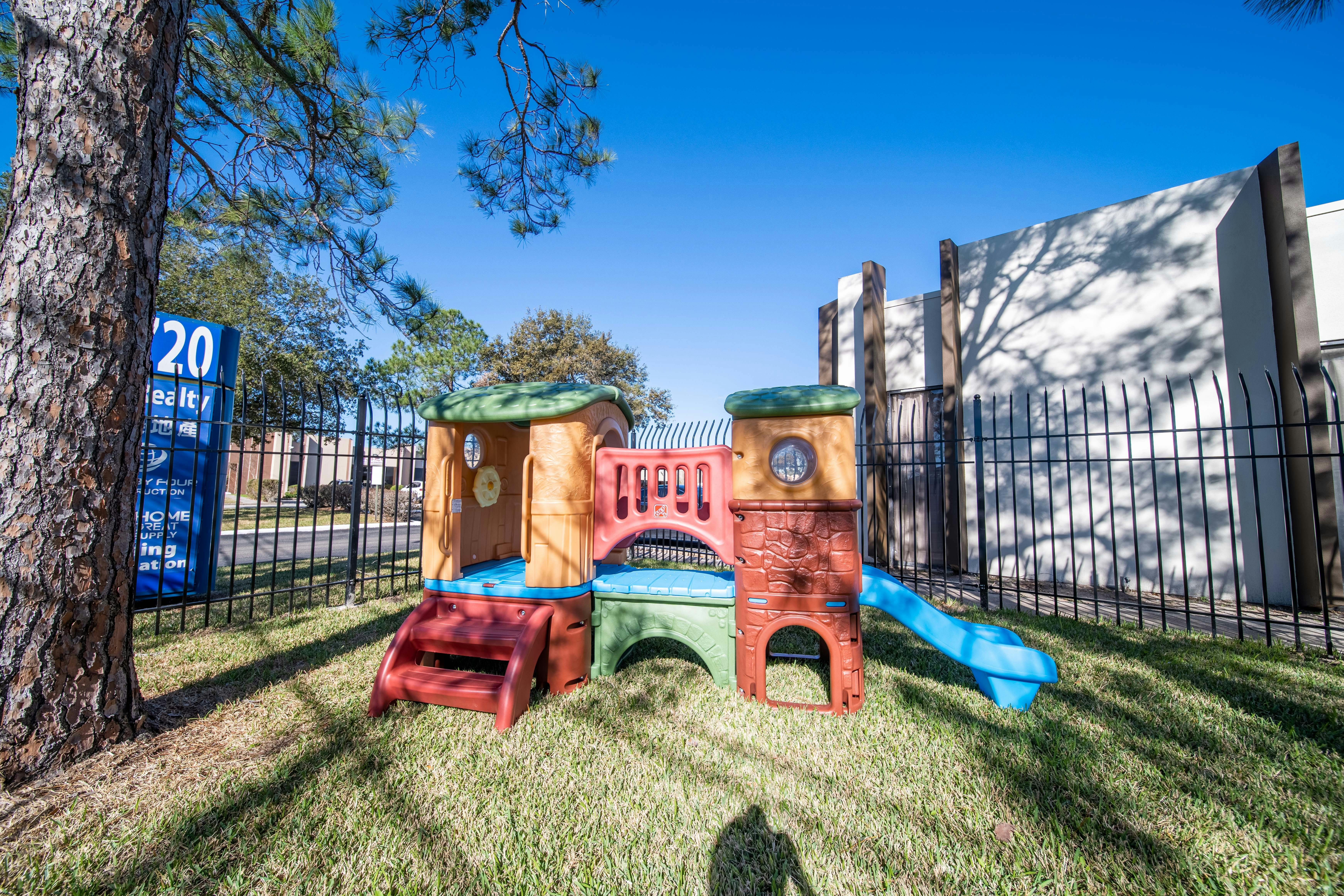 Colorful plastic children's playset with a slide and climbing areas on grass