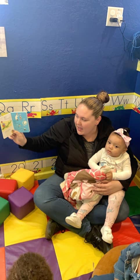 Person holding a child and reading a book in a classroom