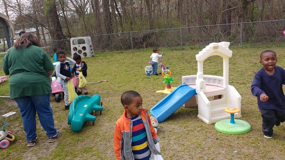 Adult and children on a playground with play equipment