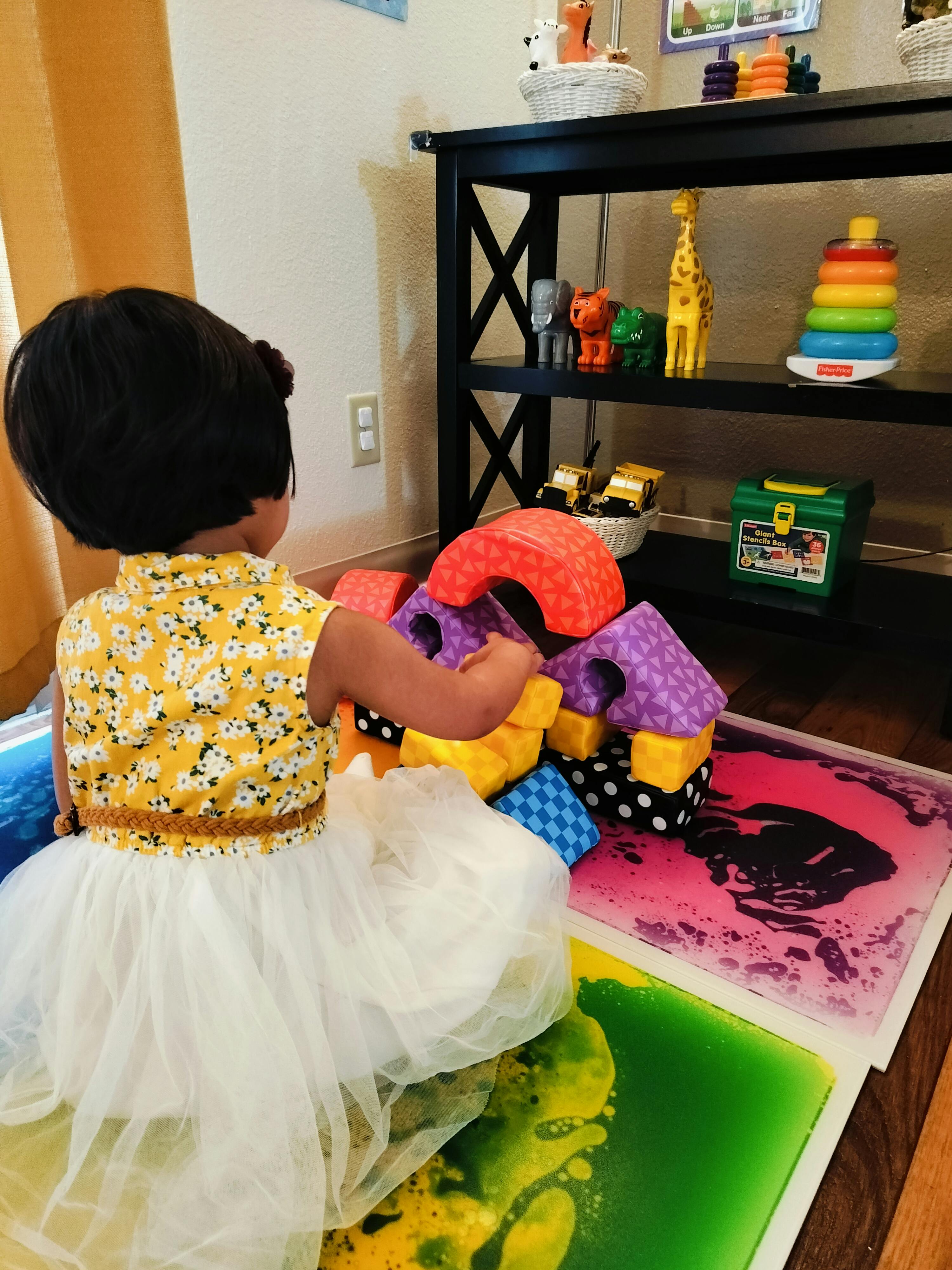 Child playing with colorful building blocks on liquid floor tiles