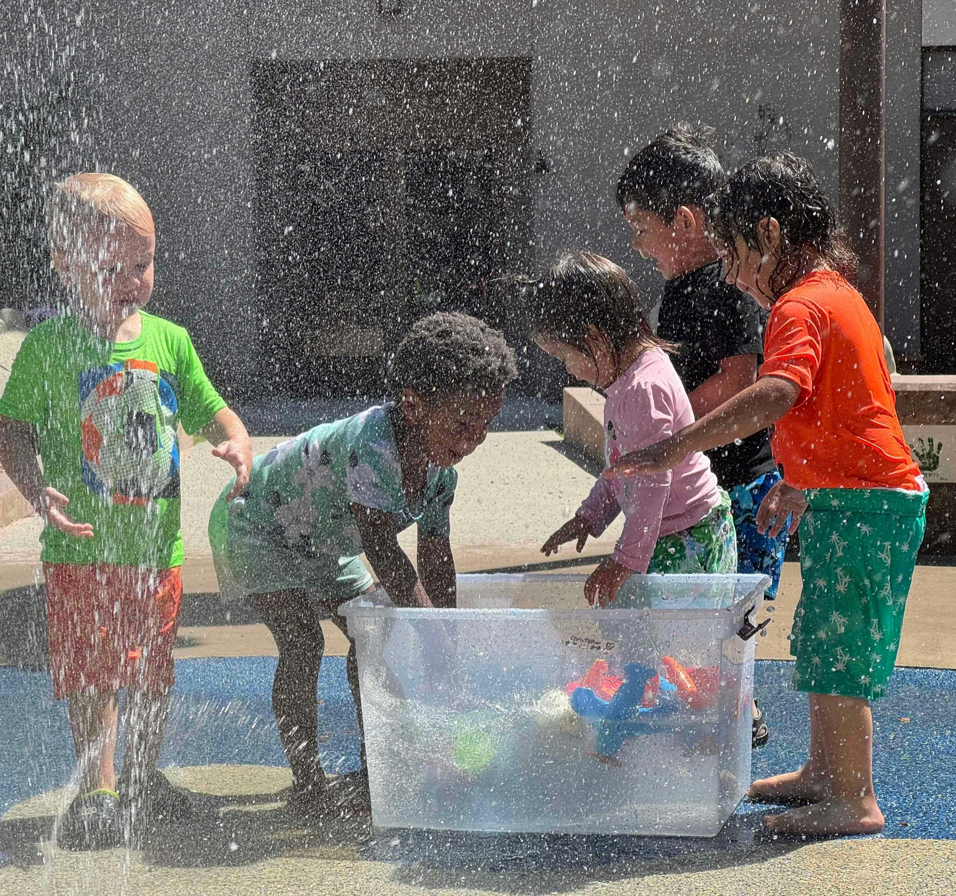 Children playing in water with a clear bin and shallow tub