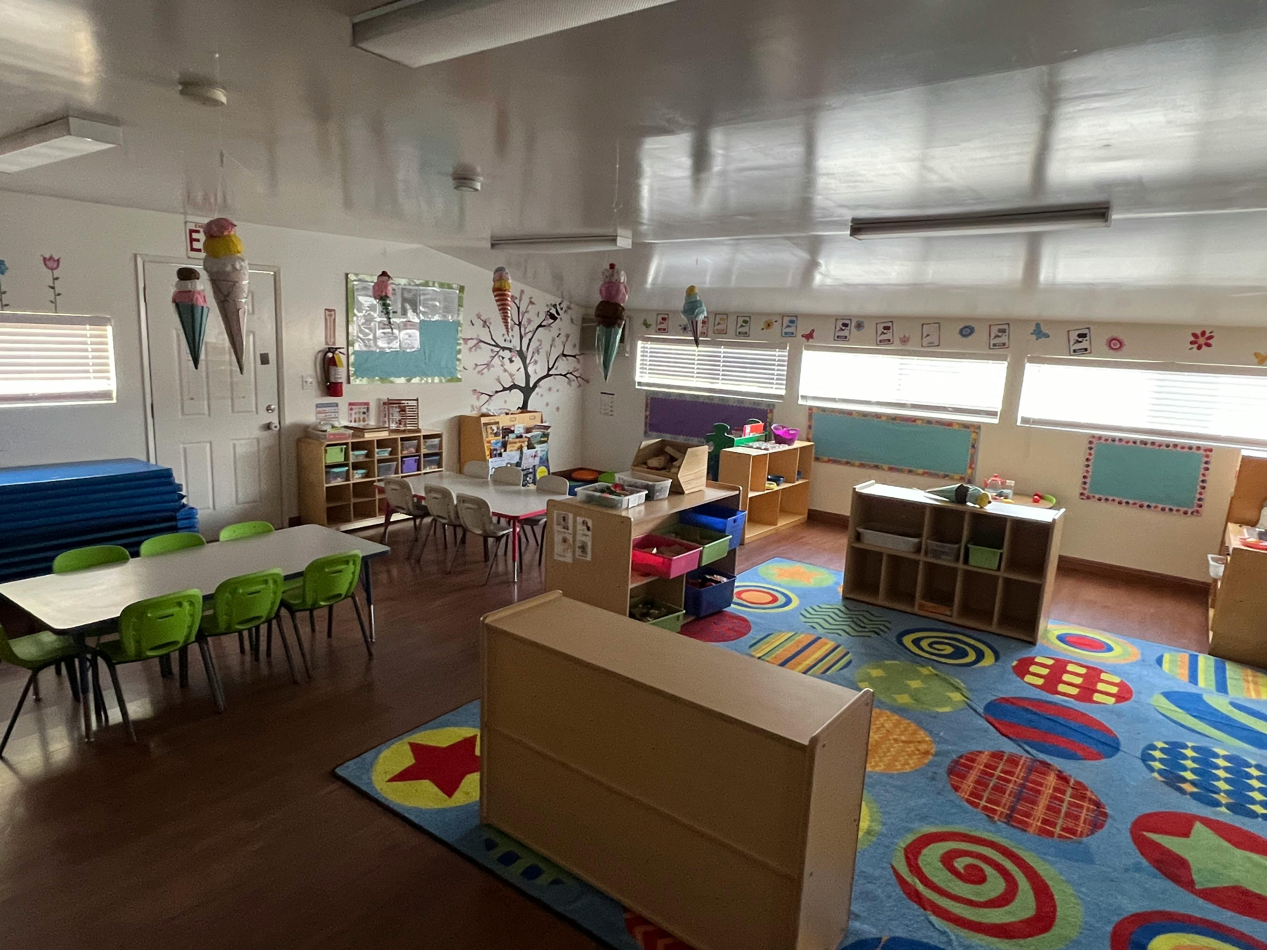 Classroom with tables, chairs, and colorful rug