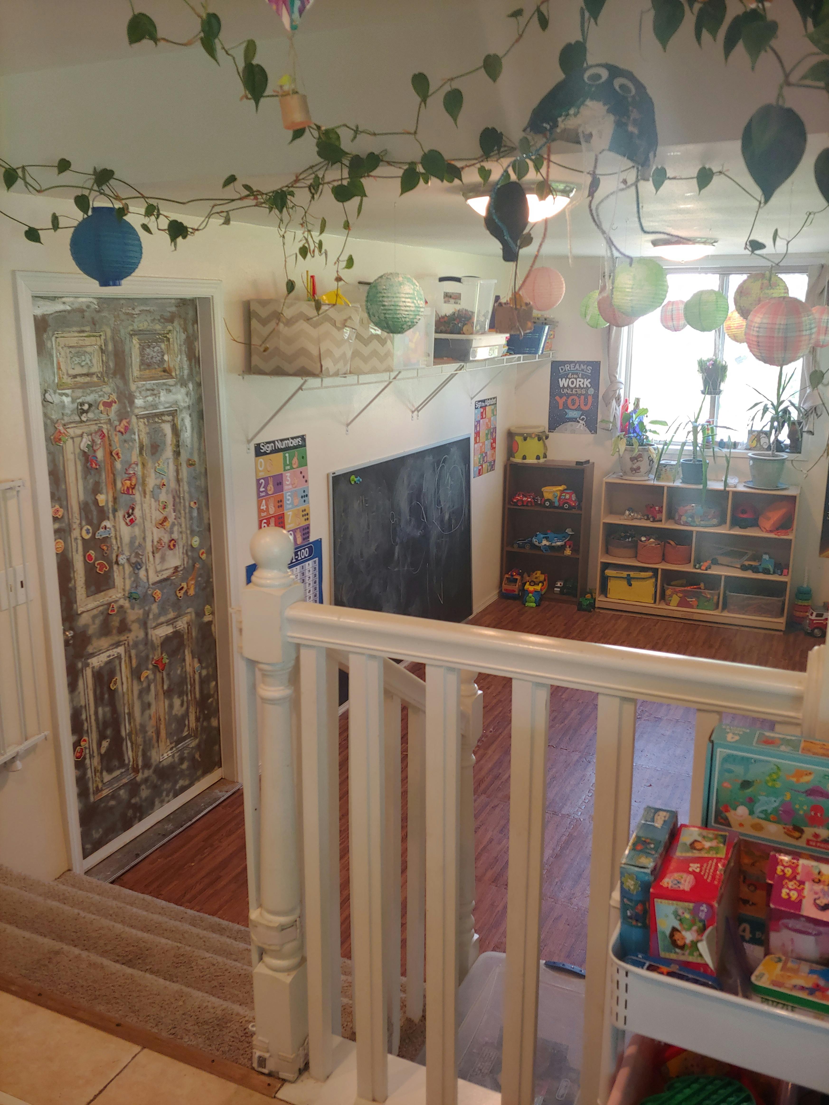 Playroom with shelves of toys, a chalkboard, and paper lanterns hanging from the ceiling