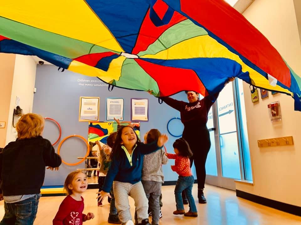 Adult and children playing with a colorful parachute