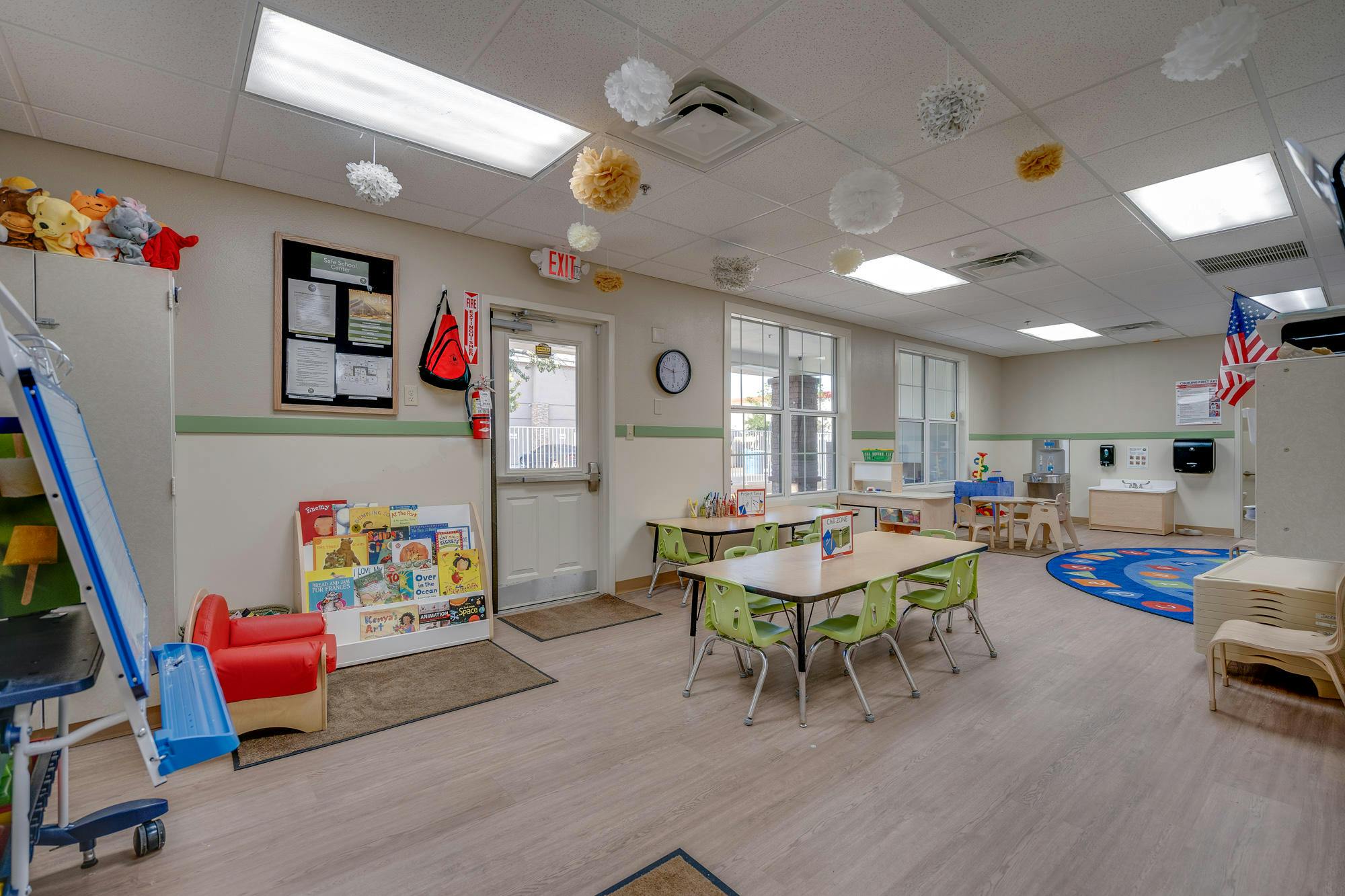 Classroom with small tables and chairs, a rug, and toys