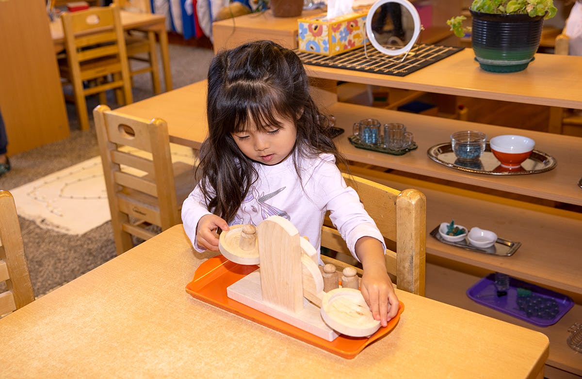 Child playing with wooden blocks on a table in a classroom