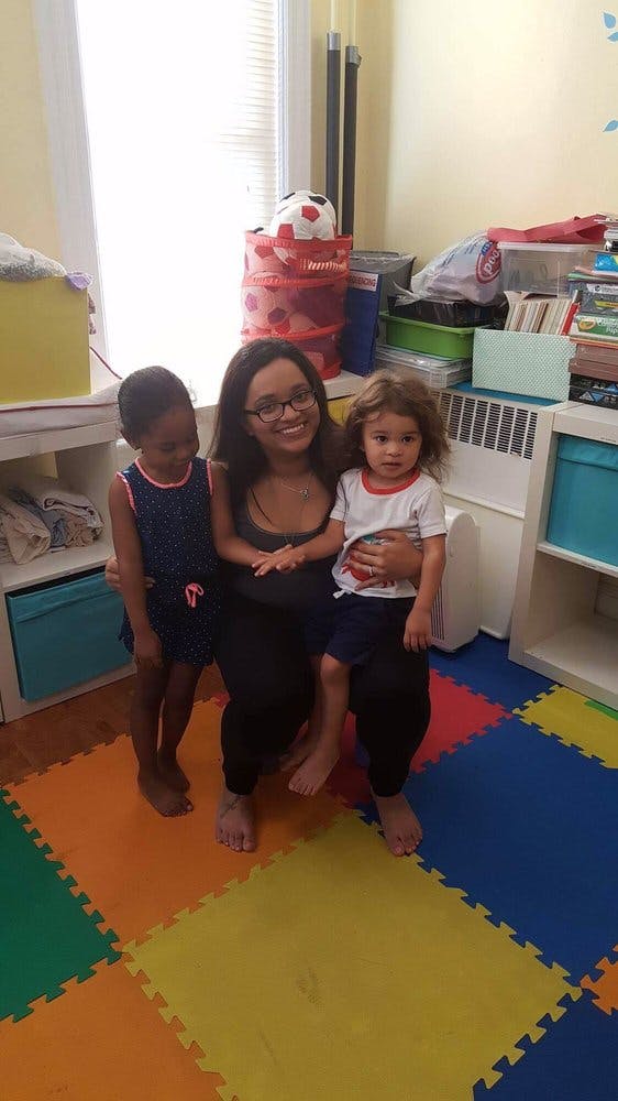 Person sitting with two children on a colorful mat