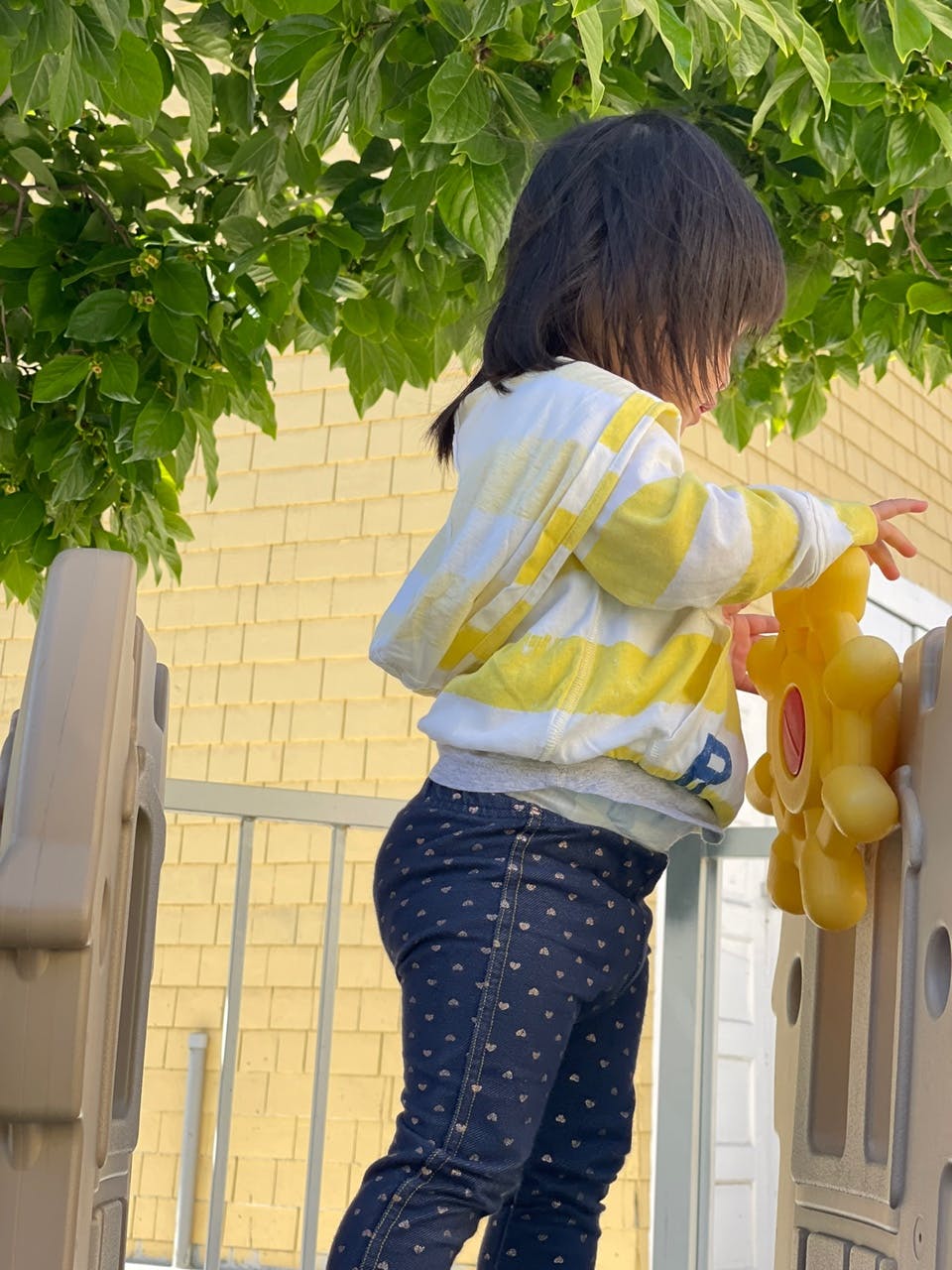Child playing with a yellow toy on a play structure